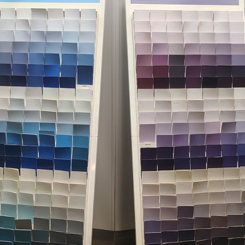Two large paint color swatch displays show graduated blue and purple shades, from pale to deep tones, in a quiet showroom setting.