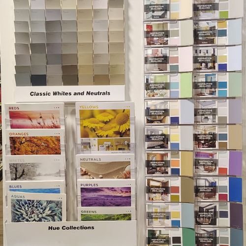 Paint store display featuring neutral color swatches, hue collection cards, and inspiration booklets arranged on a wall rack.