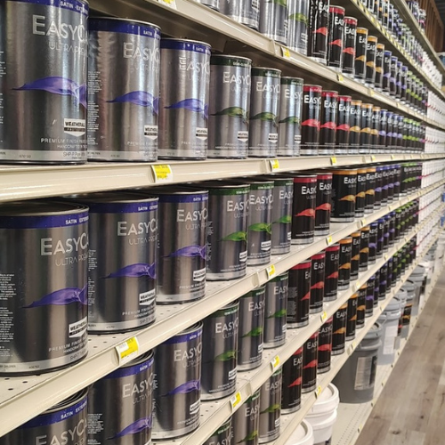Grocery store shelves display rows of EasyCoat paint cans in black, purple, green, red, and orange labels, creating an orderly aisle.